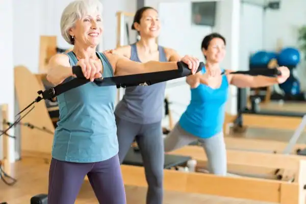 Toning Arms After 60: Empowering Womens Fitness Through Effective Weight Training 2 older woman doing weight training West Sussex and resistance in the gym to tone upper arms