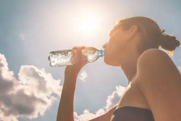 Hydration: The Secret Ingredient for a Toned Stomach and Enhanced Fitness 3 Image of woman drinking water to hydrate West Sussex after run.