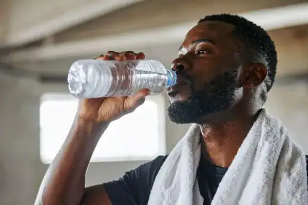 Hydration: The Secret Ingredient for a Toned Stomach and Enhanced Fitness 1 Image of man drinking water to improve hydration West Sussex after work out.